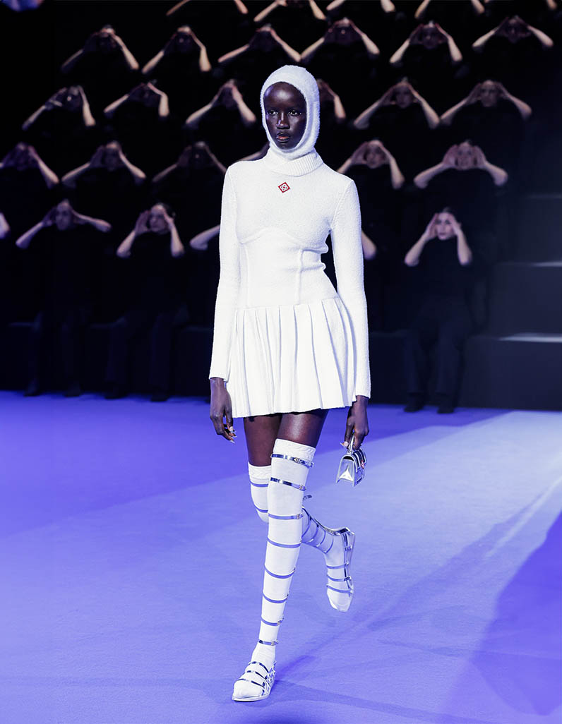 Model walks down Casablanca runway wearing white shorts and blue knitted top
